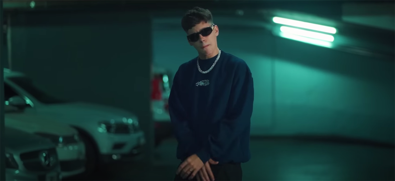 fotografía de James Rosello dentro de un estacionamiento, usando lentes de sol y una cadena